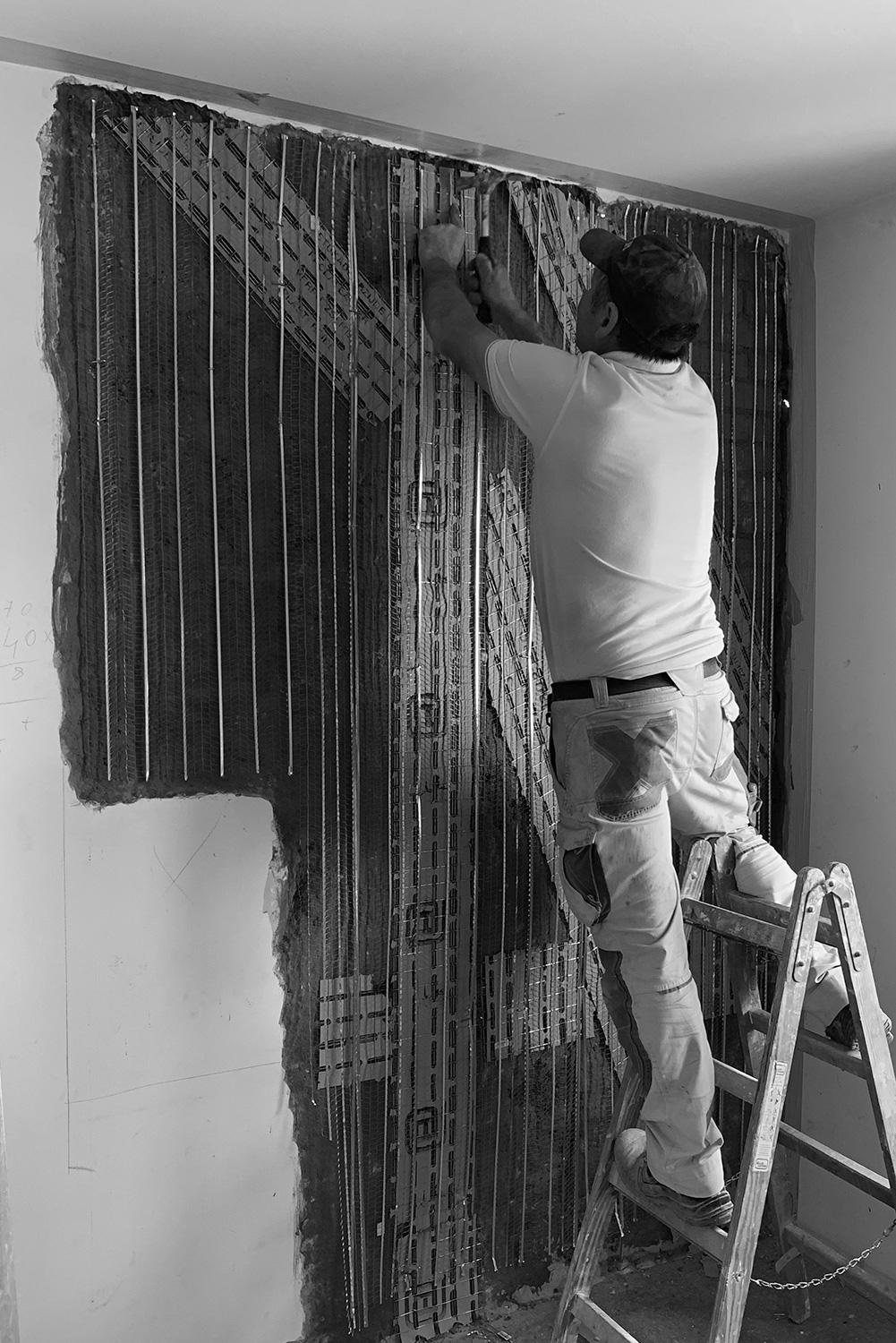 Maler, der an der Restaurierung einer Wand eines denkmalgeschützten Gebäudes aus dem 19. Jahrhundert arbeitet. 