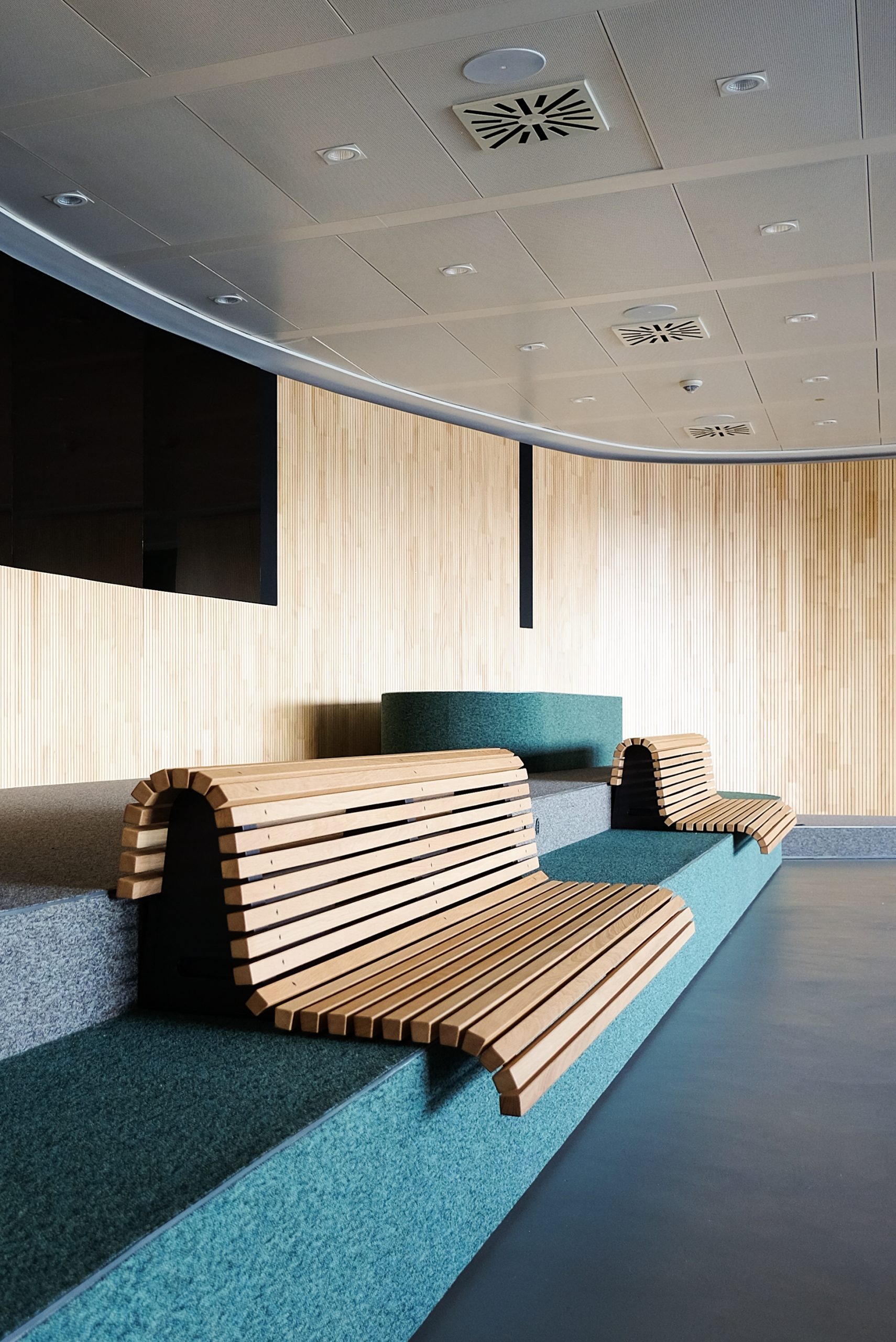 Holzbank mit modernem Design auf einem Möbelstück mit textiler Oberfläche im Besprechungsraum der Conosrsbank in Nürnberg. 