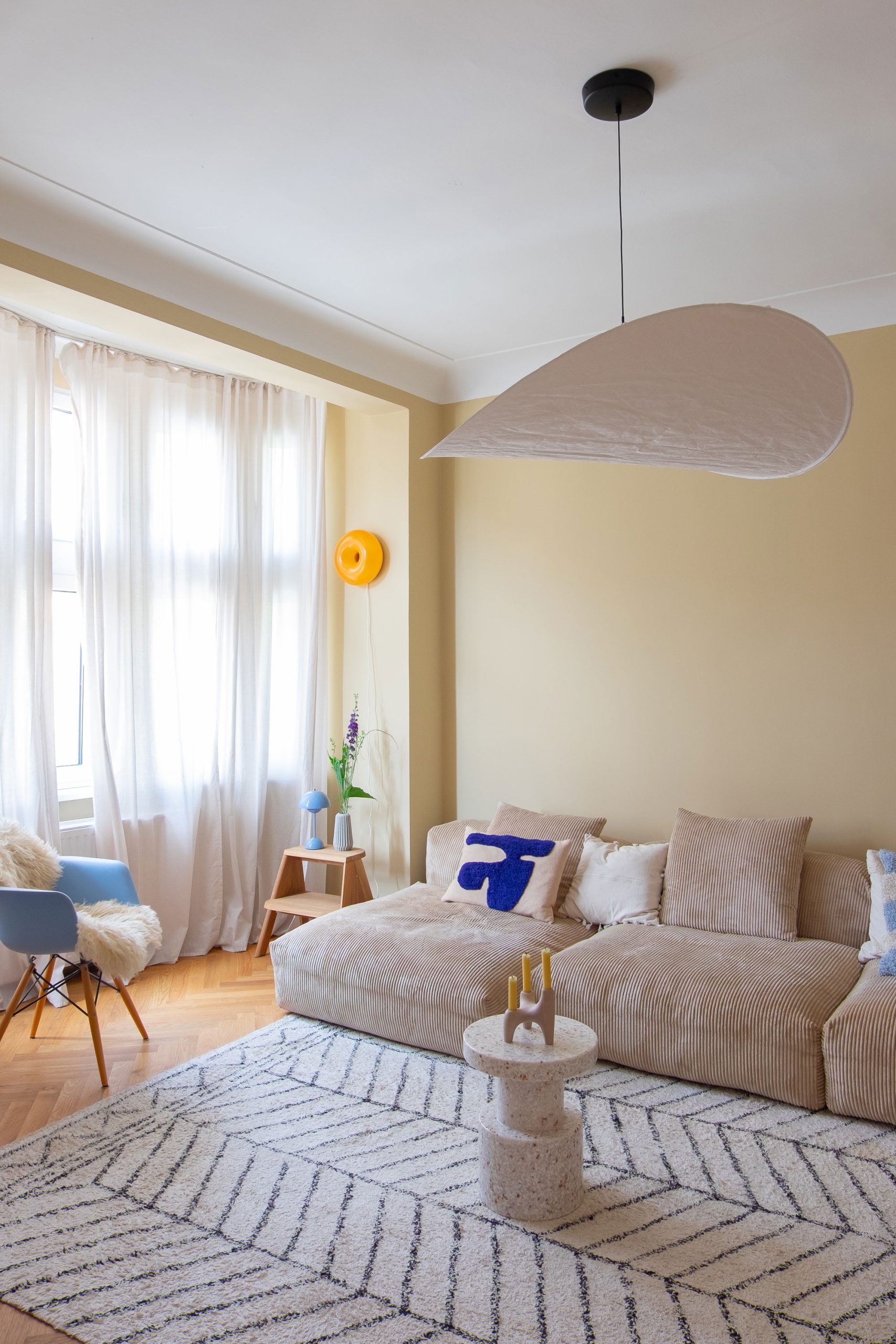 Wohnzimmer mit hellen Farben, modernem Design-Sofa und Wollteppich mit bunter Dekoration. 