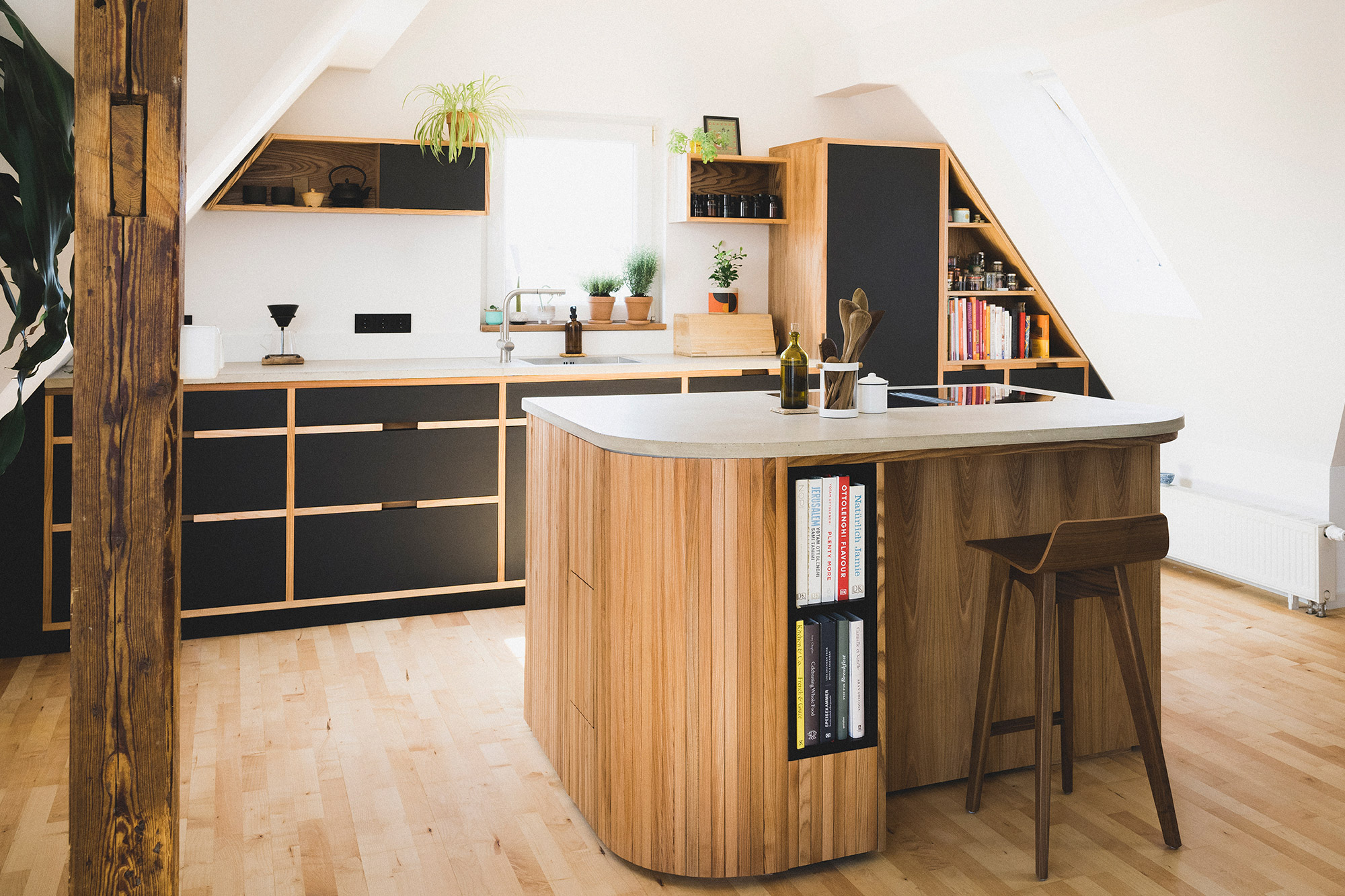 Maßgeschneiderte Küche aus Holz und Beton in einem renovierten Haus in Nürnberg mit Bücherregal und Kochbüchern.