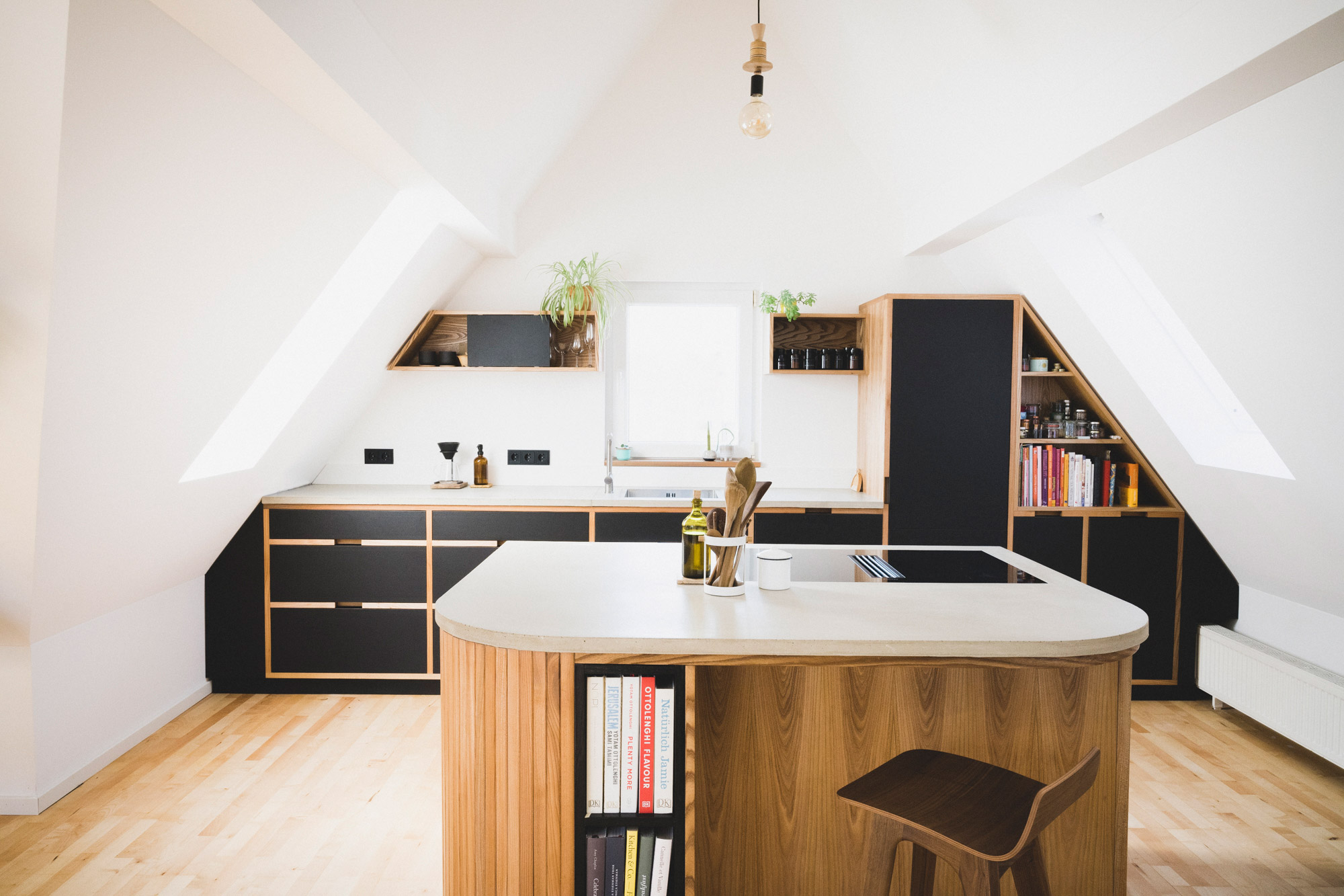Maßgeschneiderte Küche aus Holz und Beton in einem renovierten Haus in Nürnberg auf einem Parkettboden. 