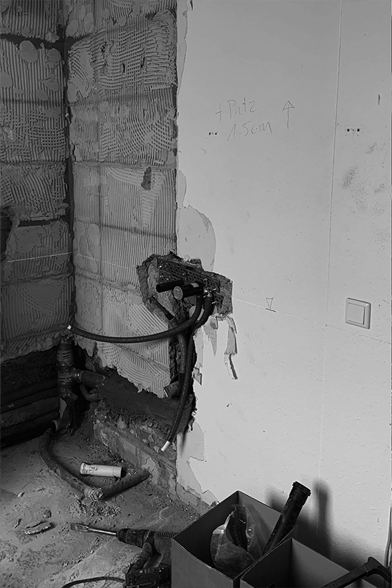 Trümmerwände in einem Badezimmer, mit alten Rohren und Fliesen. 